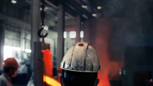 Pracownicy w odzieży ochronnej obserwują proces w odlewni.